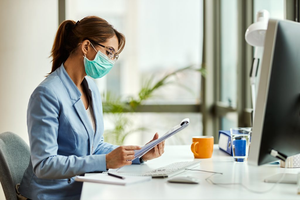 female entrepreneur with face mask analyzing business reports in